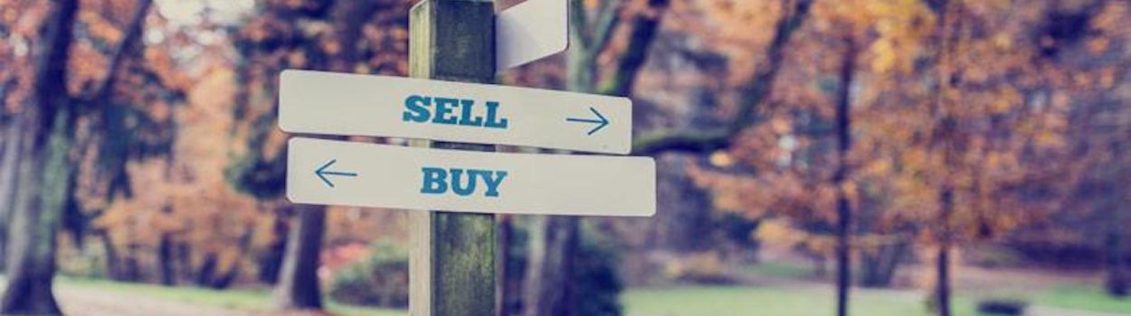 wooden post with words 'sell' and 'buy' pointing in opposite directions