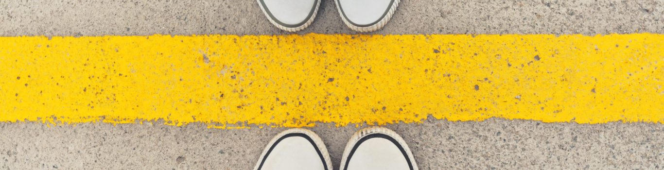 top view of yellow line on road with a pair of feet on either side