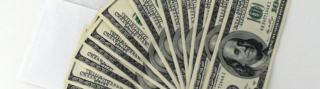 fan of dollar bills laying on top of an envelope